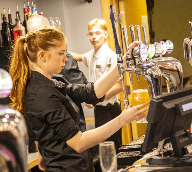 A member of bar staff at Newcastle races pouring a drink