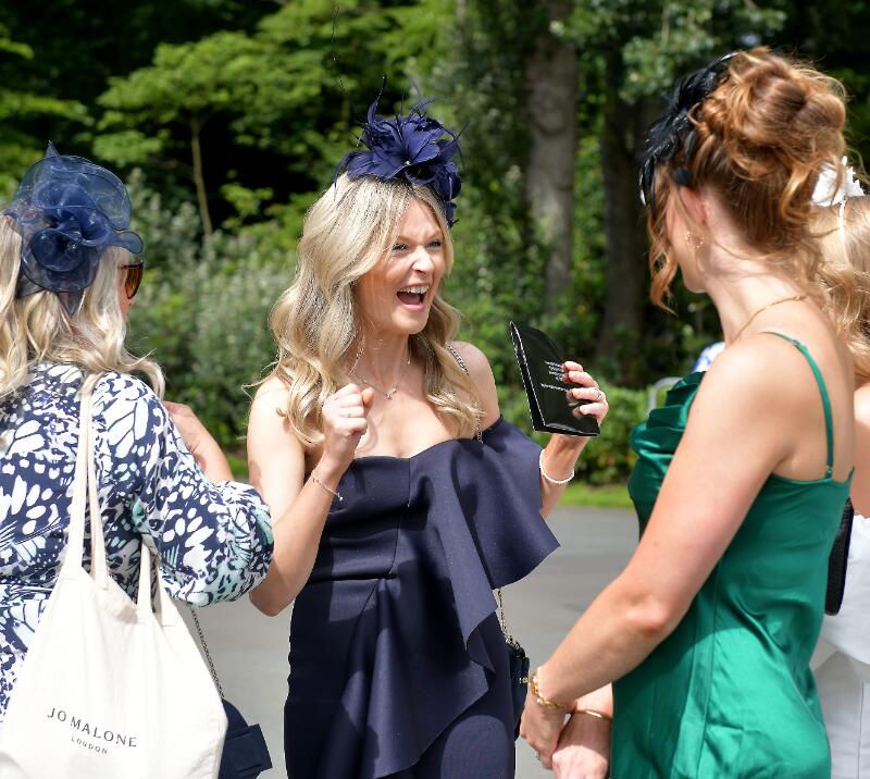 A group of ladies dressed up for the races at Newcastle chatting and smiling.