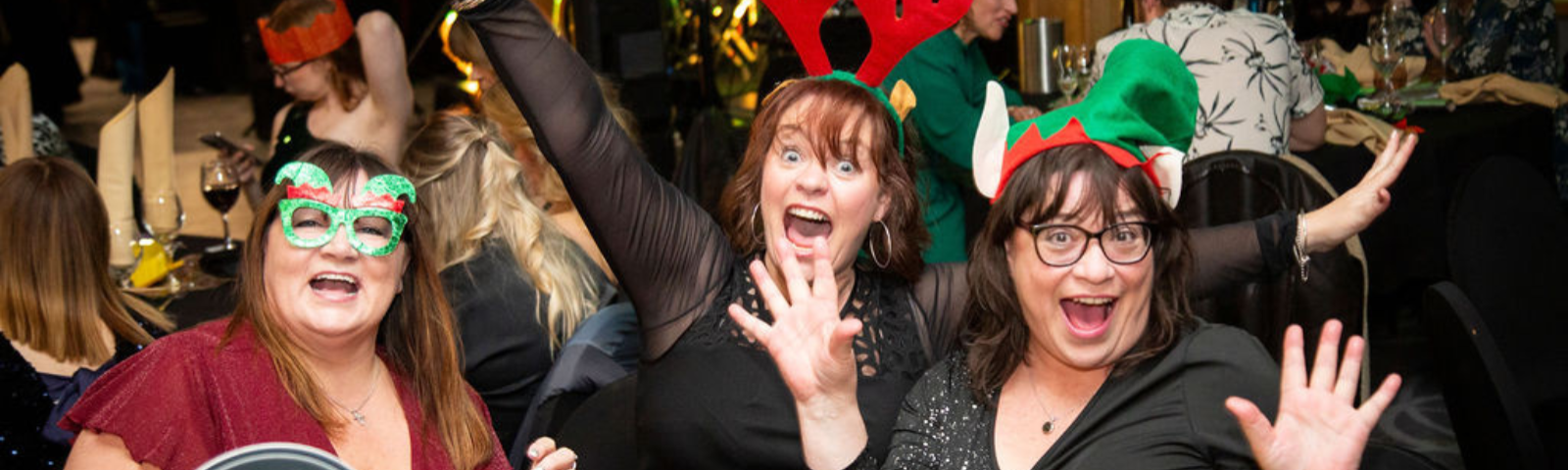 Woman sat down with festive headwear smiling and having fun at Newcastle's Christmas Party Nights.