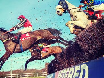 Horses with jockeys jumping over a fence at Newcastle Racecourse