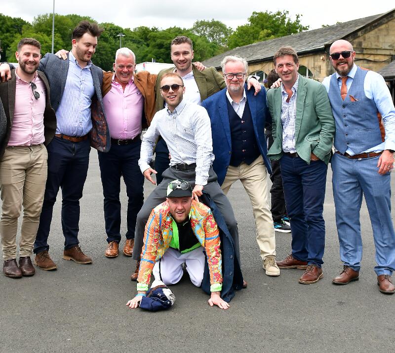A large stag do group posing for a picture at the races