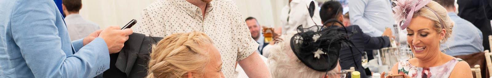 A smartly dressed group in an outdoor setting.  A lady smiles as she looks at her mobile phone.