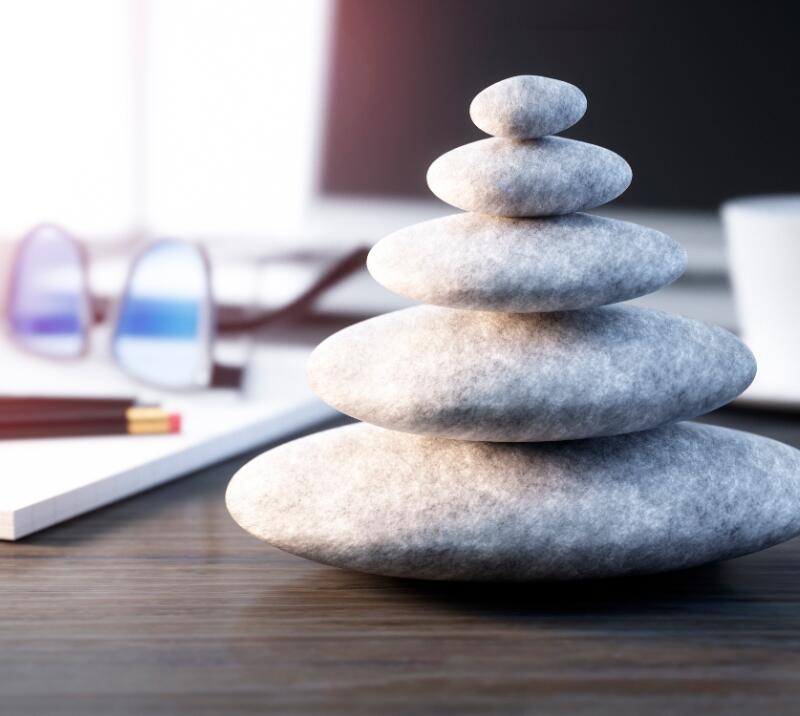 wellness/relaxation stones on desk with glasses, cup, pens, pencils and notebook