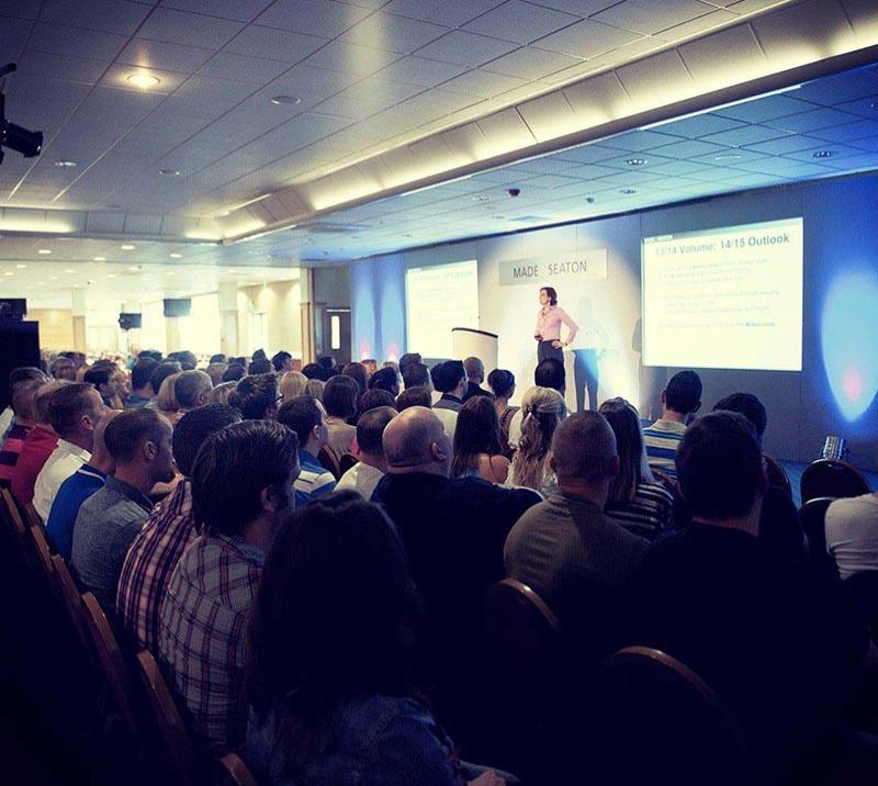 A lady presents to a seated crowd.