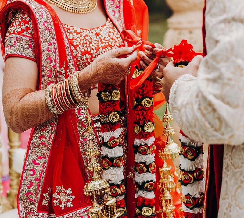 An asian couple tie bows in a red material