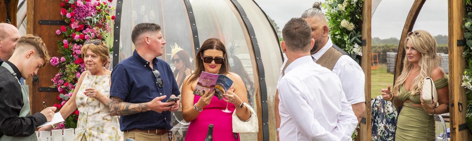A large group enjoying hospitality at Plate Festival with one reading a racecard