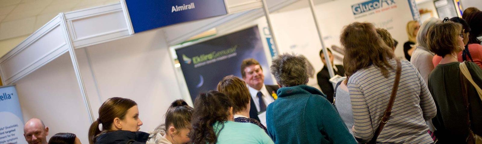 A crowd gather around an exhibition stand at Newcastle Racecourse.